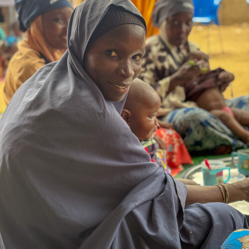 A smiling woman holds her baby.